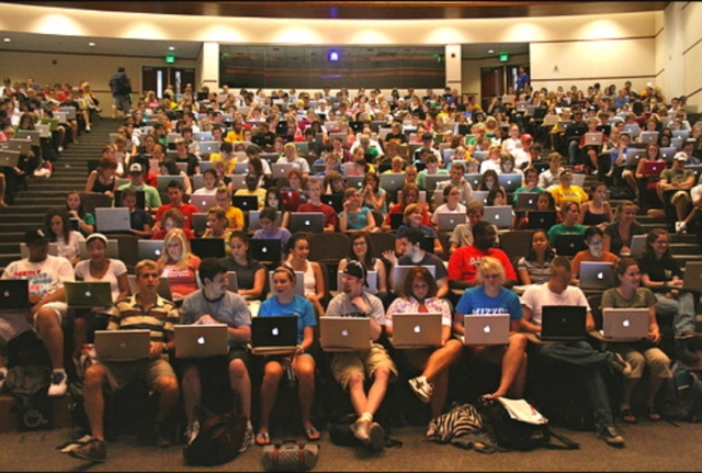 College students using MacBook laptops in a classroom