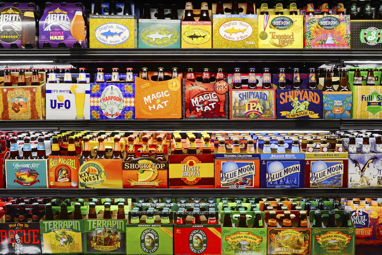 Store shelf filled with a wide variety of craft beer cans and bottles, demonstrating the overwhelming choice consumers face